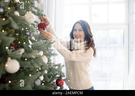 Junge hübsche lächelnde Frau schmücken Weihnachtsbaum Stockfoto