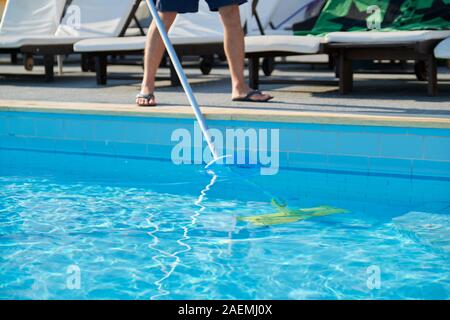 Männliche Reinigung Außenpool mit Unterwasser Unterdruckschlauch Stockfoto