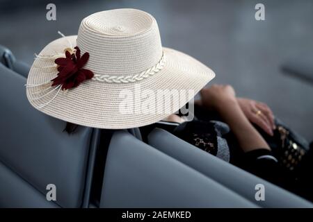 Eine Frau in einem Sommer Hut mit breiter Krempe ruht sich im Sessel des Flughafens Wartezimmer. Vietnam Stockfoto