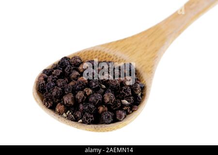 Holzlöffel voller schwarze Pfefferkörner auf weißem Hintergrund Stockfoto