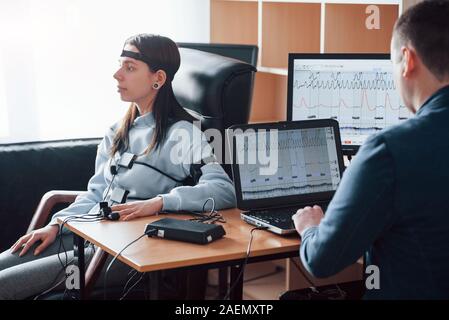 Messung von heartbeat Rate. Mädchen vergeht Lügendetektor im Büro. Fragen zu stellen. Polygraph Test Stockfoto