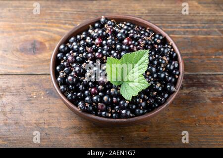 Reife schwarze Johannisbeeren in einem Ton Platte auf einem braunen Holz- Hintergrund. Platz für Text Stockfoto