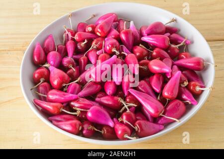 Frische Pitiguey rosa Fruchtgruppe in weißer Schale auf Holztisch. Stockfoto