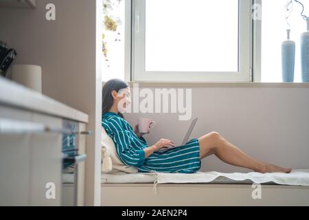 Gerne Frau mit Laptop und heißen Tee Foto Stockfoto