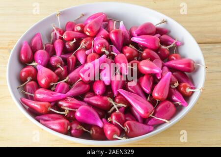 Frische Pitiguey Obstgruppe in weißer Schale auf Holztisch. Nahaufnahme Stockfoto