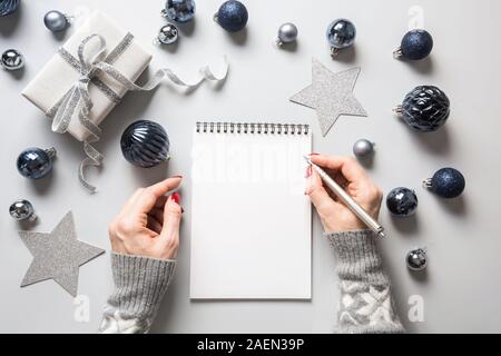 Frau schreibt Ziele, Checkliste, Pläne und Träume für das neue Jahr. Wunschliste für Weihnachten. Zur Liste für das Jahr 2020 Jahr auf Classic blau Urlaub Dekor. Geschenk ex Stockfoto