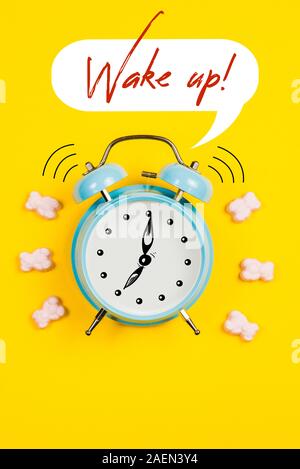 Blau Wecker mit Grafiken und Text Wake up auf gelbem Hintergrund Stockfoto