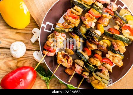 Gegrillte shashliks auf der Platte mit Huhn, becon und Gemüse Stockfoto