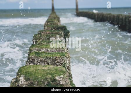 Sea Wave übergelaufen durch eine hölzerne groyne am Strand. Stockfoto