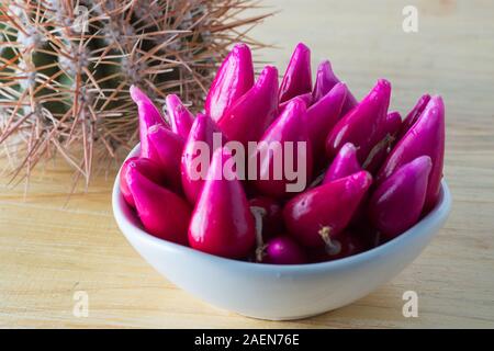 Pitiguey tropische Fruchtgruppe in weißer Schale auf Holztisch mit Kaktus. Stockfoto