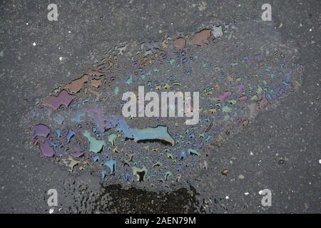 Nahaufnahme der regenbogenfarbenen Ölpest Pfützen auf dem Asphalt Stockfoto