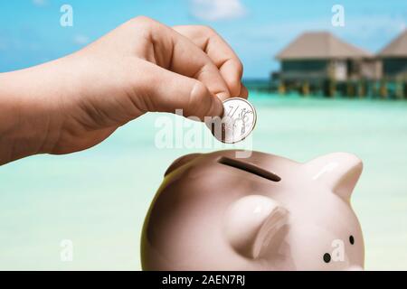 Childs, die Hand eines Rubels in ein Sparschwein. Wie viel Geld brauchen Sie für Urlaub am Meer für Russische Touristen Stockfoto