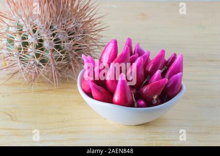 Pitiguey Obstgruppe in weißer Schale auf Holztisch mit kleinem Kaktus. Stockfoto