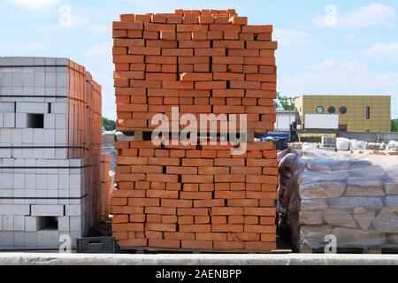 Baumaterialien. Baustoffe für den Bau der Wohnanlage. Stapel aus roten Ziegeln an der Baustelle. Stockfoto