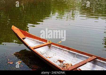 Der vordere Teil des Bootes in einem See, im Wasser widerspiegelt. Einige Blätter sind im Boot und auf der Wasseroberfläche. Stockfoto