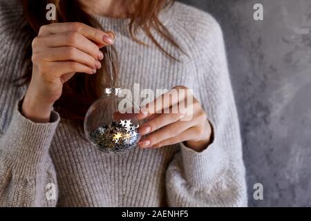 Frau mit Weihnachten Glaskugel mit glitzernden Sterne pailettes Innen, urlaub Konzept Stockfoto