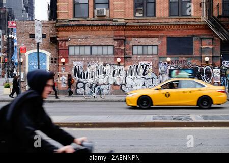 Böse oder Nett graffiti auf New York Street mit unscharfen Radfahrer und Taxi Stockfoto