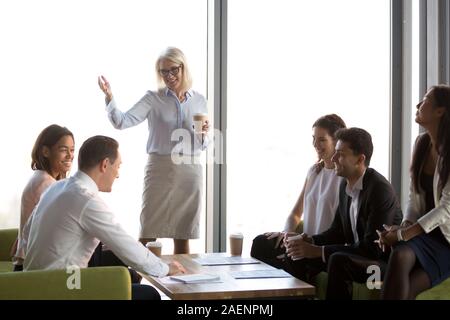 Lächelnd reife Geschäftsfrau holding Briefing mit diversen Mitarbeitern Stockfoto