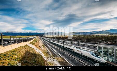 Segovia, Spanien - Dez 9, 2019: Ave-Renfe Zug zieht in Segovia Bahnhof mit schneebedeckten Bergen im Hintergrund Stockfoto