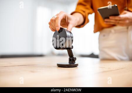 Close-up auf Wireless-IP-Kamera am Tisch zu Hause, Frau Sie ihn einschalten. Konzept der Verwaltung von Geräten per Fernzugriff von einem Smartphone Stockfoto