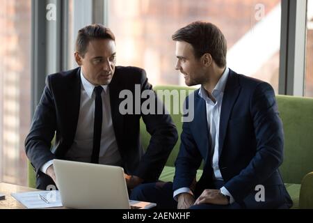 Erfolgreiche Geschäftsleute in Anzügen diskutieren online Projekt im Büro Stockfoto