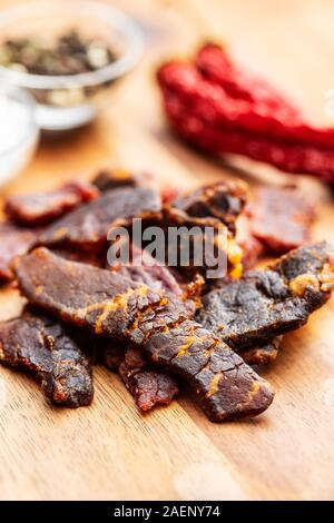 Beef Jerky Stücke. Getrocknetes Rindfleisch auf hölzernen Tisch. Stockfoto