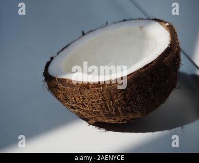 Die zerbrochene Kokosnuss in einer Neonfarbe als Hintergrund, fertige Karte Stockfoto