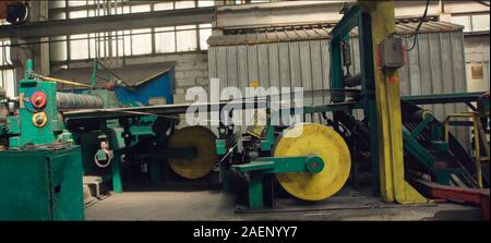 Altes Blech schneiden Maschine für die Herstellung von Stahlrohren, Rohren und Profilen aus Metall im Werk. Verpackt Rollen aus Stahlblech spulen. Stockfoto