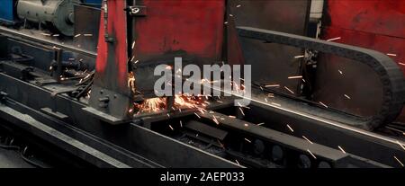 Blech schneiden/forming Maschine für die Herstellung von Stahlrohren, Rohren und Profilen aus Metall im Werk. Die Funken zu der Seite bröckeln. Konzept fo Stockfoto