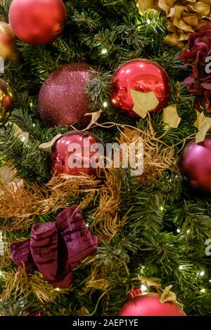 Nahaufnahme der Weihnachtsbaum mit farbenfrohen roten Purpur und Gold Flitter und Dekorationen. Stockfoto