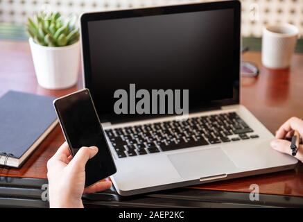 Handy und Laptop mit schwarzen Leere Bildschirme, Mann bei der Arbeit in seinem Büro Schreibtisch, geschäftlichen Hintergrund, kopieren. Stockfoto