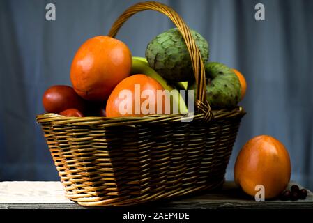 Weidenkorb mit Herbst Früchte und Zitronen Stockfoto