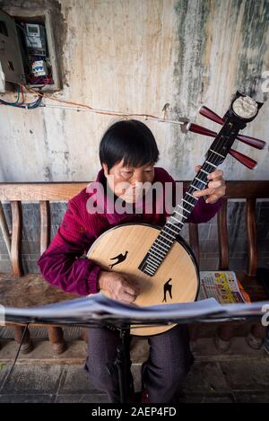 März 7, 2019: Ältere chinesische Frau spielen eine Traditionelle Chinesische Musikinstrument in Jianshui, Yunnan, China Stockfoto