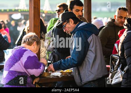 Menschen ein Mittagessen mit rumänischen traditionellen Essen in Bukarest Weihnachtsmarkt. Bukarest, Rumänien, 2019. Stockfoto