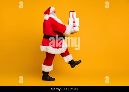 Volle Länge Profil Seite Foto, lustig, dicke weiße bärtige Santa Claus Weihnachten Geschenkset halten damit er Leute vom Nordpol gehen holen Sie auf x-mas Night Stockfoto