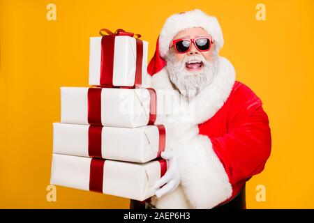 Portrait von Lustige funky graue Haare santa claus in Red Hat Pakete halten bringt er für gute Kinder Menschen feiern Neujahr holly Weihnachten Zeit isoliert Stockfoto