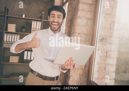 Portrait von positiven indischer Geschäftsmann Rechtsanwalt verwenden Halten Sie laptop genehmigen neue effektive Seminar Workshop tolle Teamarbeit Training zeigen Daumen hoch Verschleiß Stockfoto