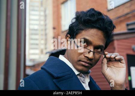 Hübscher junger gemischter Rasse Mensch über seine Brille. Stockfoto