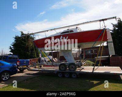 Eine kleine Racing Yacht von Straße auf einem Tieflader mit einem 4x4 Pickup truck transportiert. Stockfoto