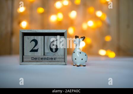 Cube Holz- Kalender mit Datum vom 26. Dezember mit keramischen Rentier Figur über bokeh Hintergrund. Adventskalender, Weihnachten Hintergrund Stockfoto