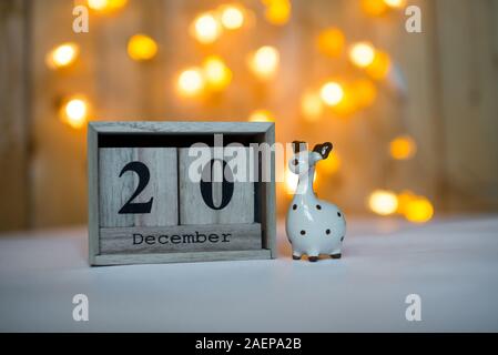 Cube Holz- Kalender mit Datum vom 20. Dezember mit keramischen Rentier Figur über bokeh Hintergrund. Adventskalender, Weihnachten Hintergrund Stockfoto