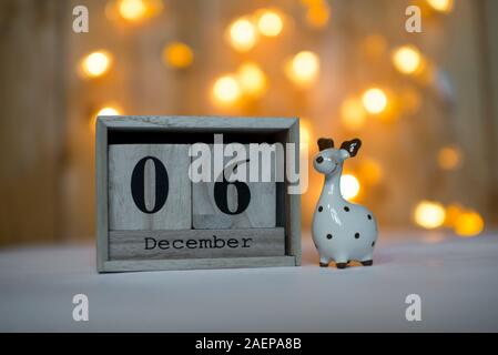 Cube Holz- Kalender mit Datum am 6. Dezember mit keramischen Rentier Figur über bokeh Hintergrund. Adventskalender, Weihnachten Hintergrund Stockfoto