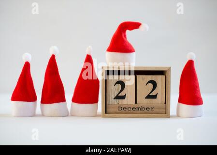 Cube Holz- Kalender mit Datum des 22. Dezember mit kleinen santa Hüte auf weißem Hintergrund. Adventskalender, Weihnachten Hintergrund, Kopieren Raum Stockfoto