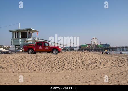 Rettungsschwimmer parken am Strand mit Rettungsschwimmturm und Santa Monica Pier im Hintergrund, Kalifornien, USA Stockfoto