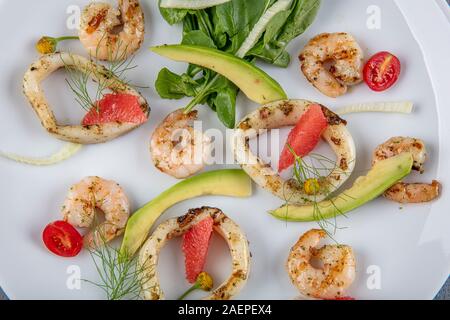 Fischplatte mit Frittierte Tintenfischringe, Garnelen mit Zitrone auf frischen Rucola. Mediterrane Vorspeisen. Ansicht von oben Stockfoto