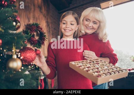 Portrait von Nizza attraktive Bezaubernd, charmantes, süß Heiter Heiter verträumt Granny vor - jugendlich Enkelkind hängenden Spielzeug auf Tanne Ausgaben Tag an eingerichtet Stockfoto