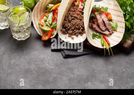 Der mexikanische Tacos mit Fleisch und Gemüse in Tortilla. Und Caipirinha Cocktail. Auf Stein Tisch mit Platz kopieren Stockfoto