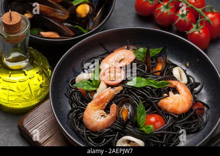 Schwarze spaghetti Pasta mit Meeresfrüchten, Tomaten und Basilikum Stockfoto