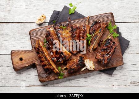 Grill Rindfleisch Rippen mit BBQ Sauce in Scheiben geschnitten auf einem Holzbrett. Ansicht von oben flach Stockfoto