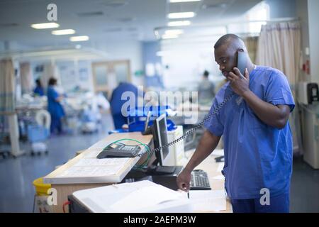 Eine Krankenschwester an einer Arbeitsstation in einem NHS Krankenstation. Der NHS ist zunehmend unter Druck, mit Mangel an der Finanzierung. Stockfoto